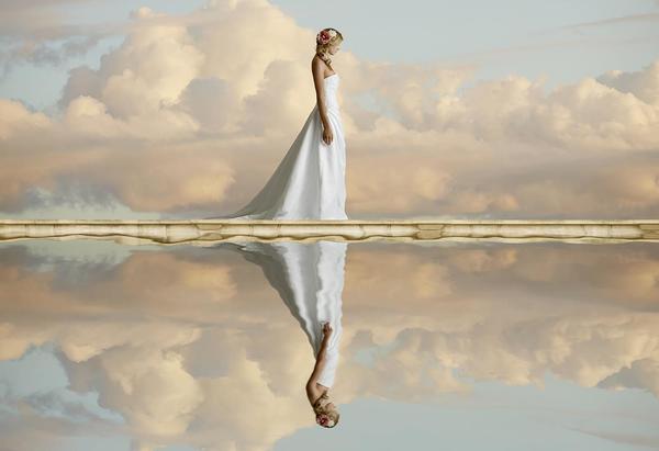 woman in wedding dress reflected in water