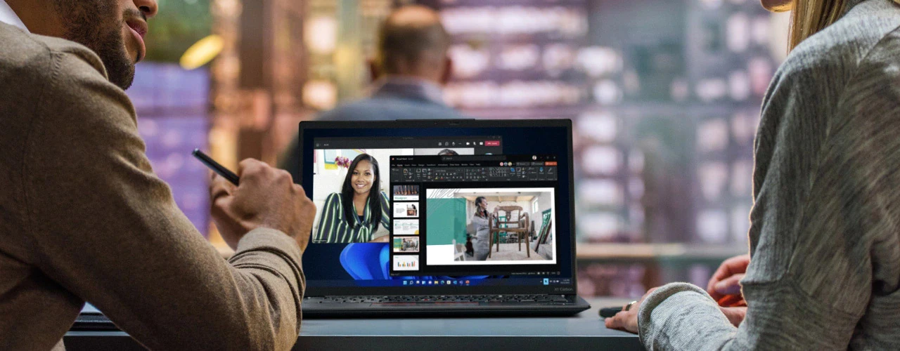 Tight over-the-shoulder shot of two people using a Lenovo ThinkPad X1 Carbon laptop for a video conference