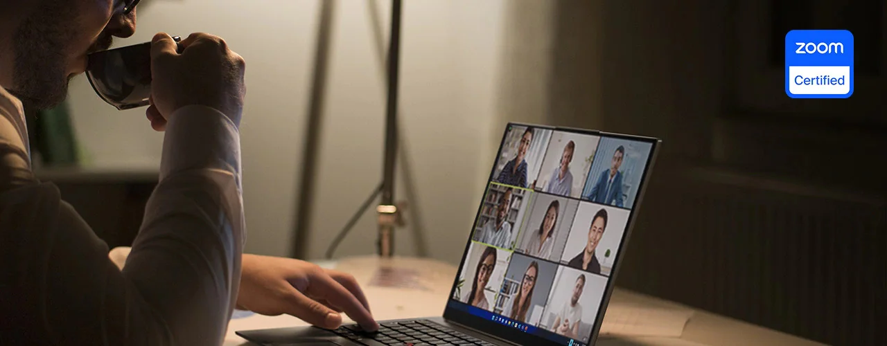 Close-up of a person drinking from a mug while using a Lenovo ThinkPad X1 Carbon laptop for a video conference